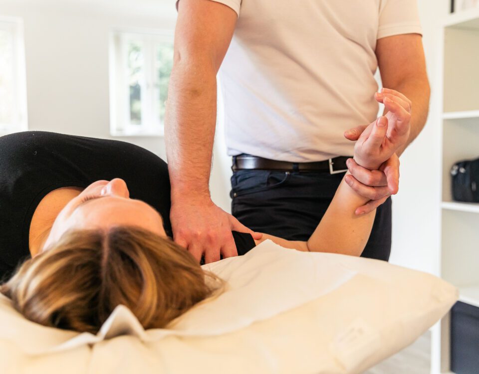 Osteopath palpating a patient’s shoulder during a hands‑on OMT session at their osteopathy appointment